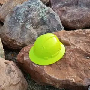 A yellow hard hat sits on top of rocks.