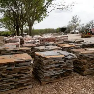 A large pile of Oklahoma Blue - Brown Flagstone B GRADE is stacked in a yard.