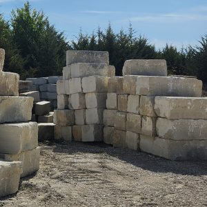 A bunch of 18" Cottonwood Split, Milled/Sawn, with one sawn end stacked in a dirt field.