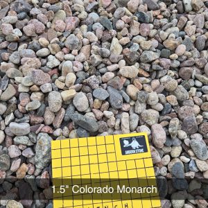A collection of small, multicolored pebbles with a yellow measurement card in the foreground reading "1 inch squares" and "1.5" Colorado Monarch.