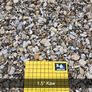 A pile of small gray and brown rocks is displayed with a yellow grid chart labeled "1.5'' Kaw" and "1 inch squares" from Andor Stone, indicating the size of the stones.